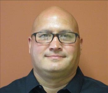 Bald male SERVPRO employee with dark eyes and glasses