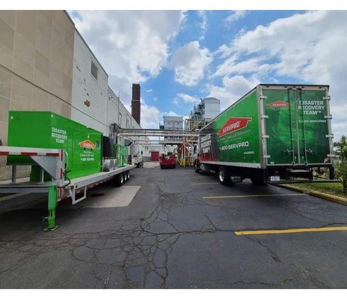 SERVPRO green vehicles and semis in a parking lot.
